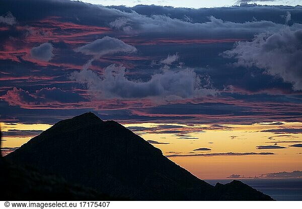 Glühender Abendhimmel über Berggipfel  Abendrot  dramatische Abendstimmung  Sonnenuntergang mit Wolken über dem Meer  Blick vom Gipfel des Hermannsdalstinden  Moskenesöy  Lofoten  Nordland  Norwegen  Europa