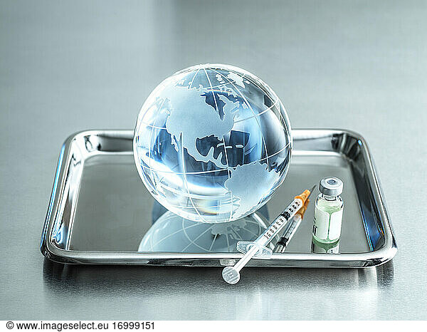 Gläserne Erdkugel mit Impfung in einem Tablett auf einem Tisch im Krankenhaus
