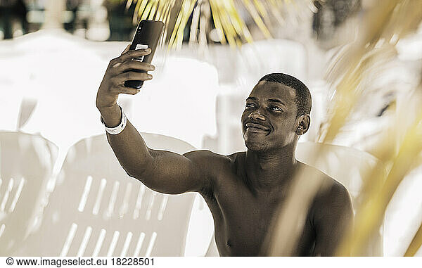 Glad black tourist taking selfie on beach