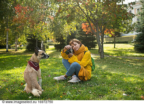 Glad woman taking photos of dog in park