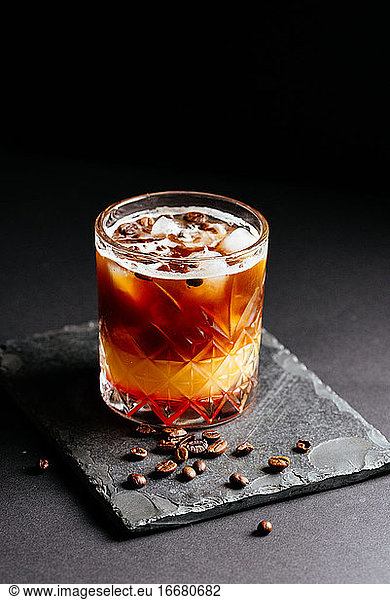 Glas alkoholischer Coctail mit Eis auf schwarzem Hintergrund
