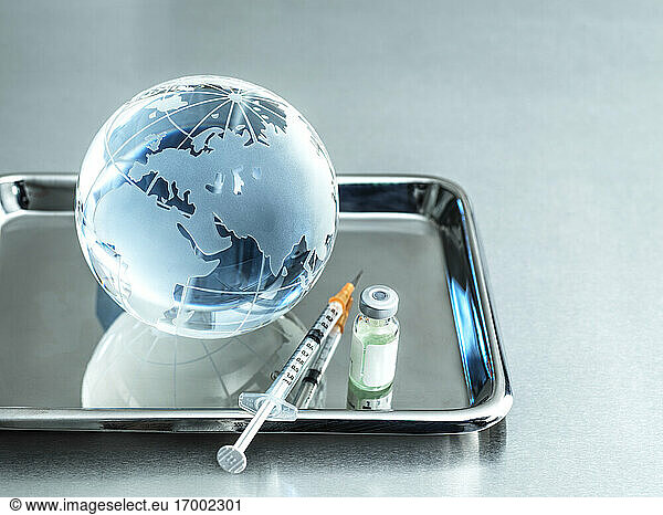 Glaskugel mit Injektion und Fläschchen im Tablett auf dem Tisch