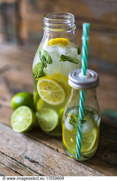 Glass bottles of infused water with lemon  lime  mint leaves and ice cubes