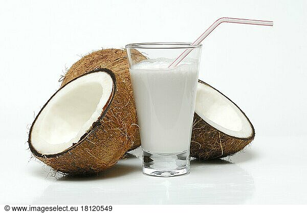 Glass of coconut milk  halved coconut  drinking straw  coconut milk