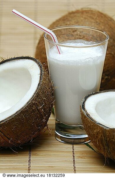 Glass of coconut milk  halved coconut  drinking straw  coconut milk