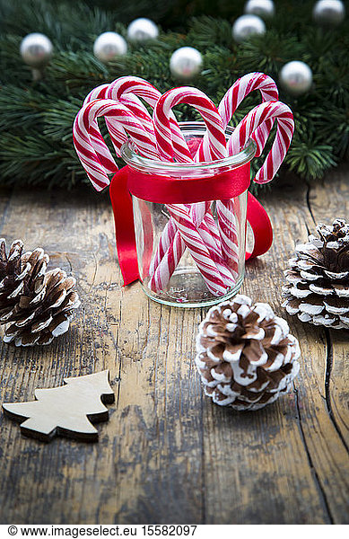 Glass of sugar canes and fir cones on wood