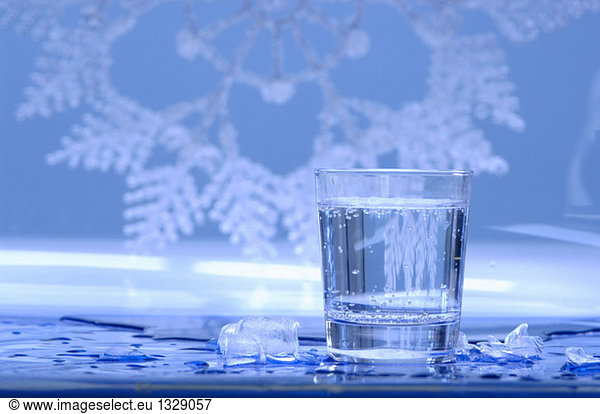 Glass of water with ice cubes around  close-up