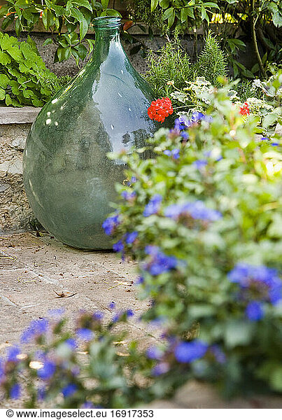 Glass vase with flower pots on terrace in garden.