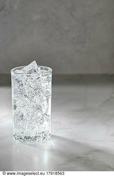 Glass with mineral water with ice on marble background