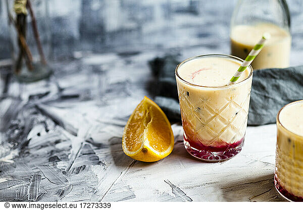 Glasses of fresh fruit smoothie with oranges  bananas  yogurt and grenadine