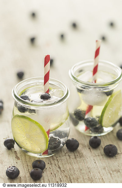 Glasses of infused water with lime  blueberries and ice cubes