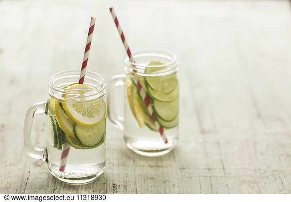Glasses of infused water with lime  lemon  cucumber and ice cubes