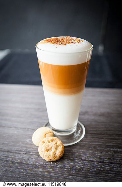 Glasses of latte macchiato and biscuits on table