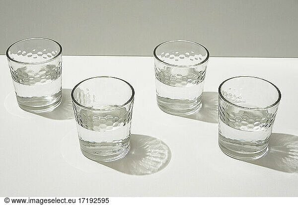 Glasses with water casting shadows and sparkles on the white table.