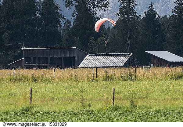 Gleitschirmflieger kommen an einem sonnigen Tag zur Landung auf einem Feld.