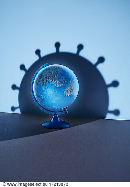 Globe casting large blue coronavirus bacterium shadow