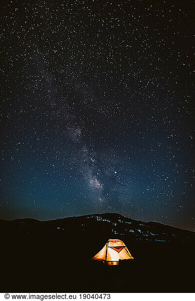 glowing orange tent under a clear nights sky with milky way
