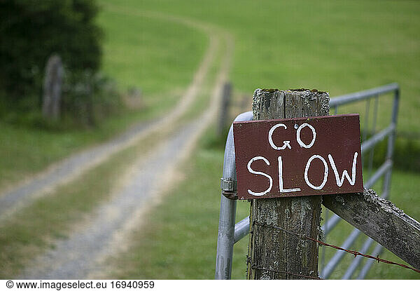 Go slow sign on wooden countryside gate.