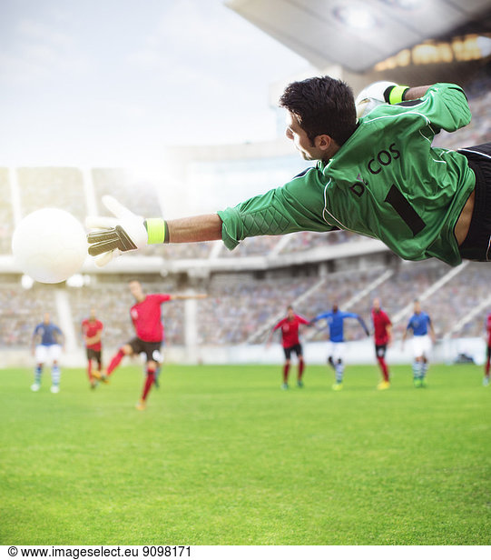 Goalie reaching for ball in mid-air on soccer field