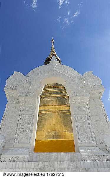 Gold painted chedi at Wat Suan Dok  white stone archway and tall tapered tower.