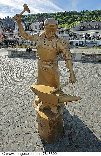 Golden sculpture as goldsmith and locksmith working steel at an anvil with hammer in Alf  Moselle  Untermosel  Rhineland-Palatinate  Germany  Europe