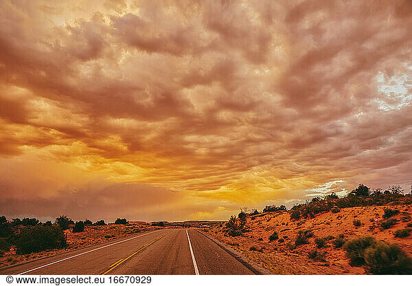 Golden sunset over storm clouds along empty highway in Moab  Utah.