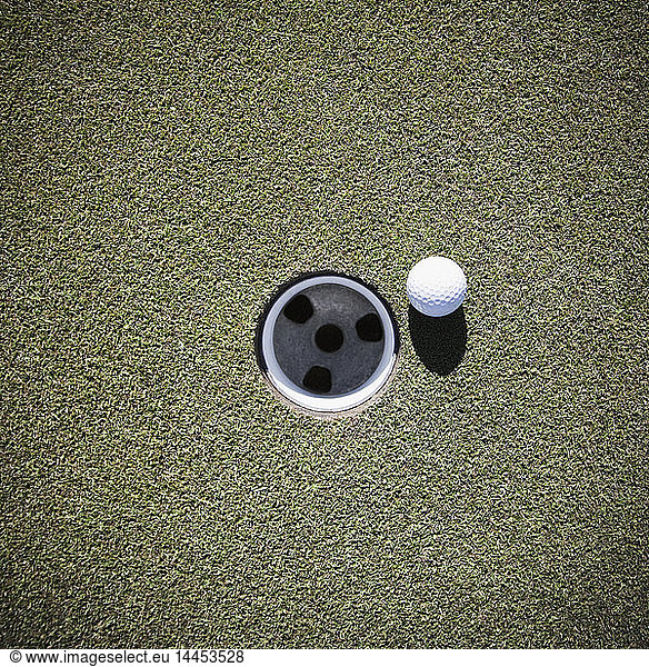 Golf Ball Next to a Putting Cup