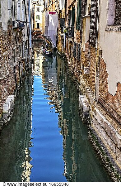 Gondel und Touristen in bunten kleinen Kanal schafft schöne Reflexionen in Venedig Italien.