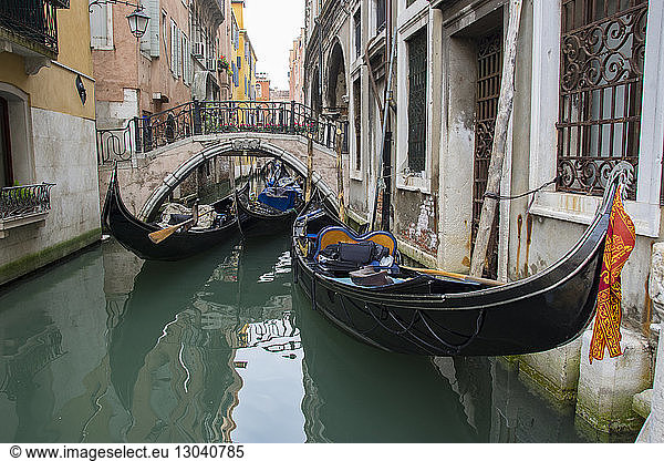 Gondolas in narrow canal by buildings