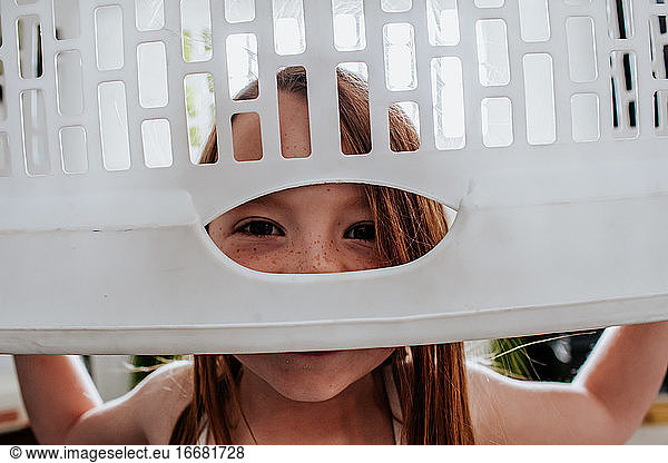 goofy cute child peeking through laundry basket