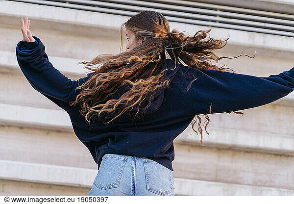 Gorgeous Girl Dancing Backwards Next To A Concrete Wall.
