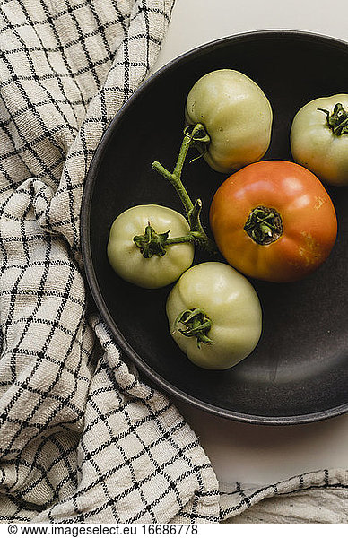 Grüne und orangefarbene Tomaten aus eigenem Anbau in einer schwarzen Schale