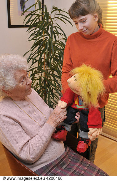 Granddaughter and grandmother playing together with a doll ...