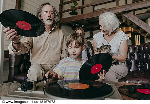 Granddaughter changing record on turntable with grandparents at home
