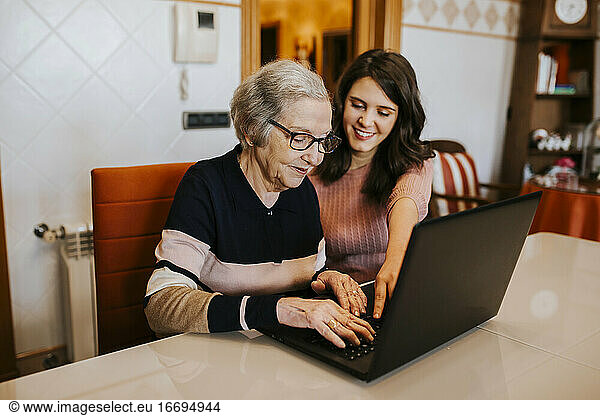 granddaughter teaching her grandmother something on the laptop