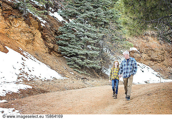 Grandfather and Granddaughter Holding Hands on a Walk in the Mountains