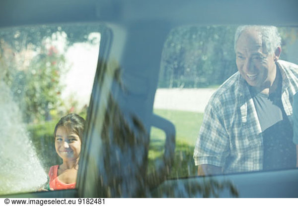 Grandfather and granddaughter outside car