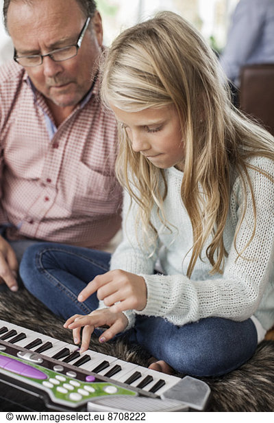 Grandfather and granddaughter playing piano at home