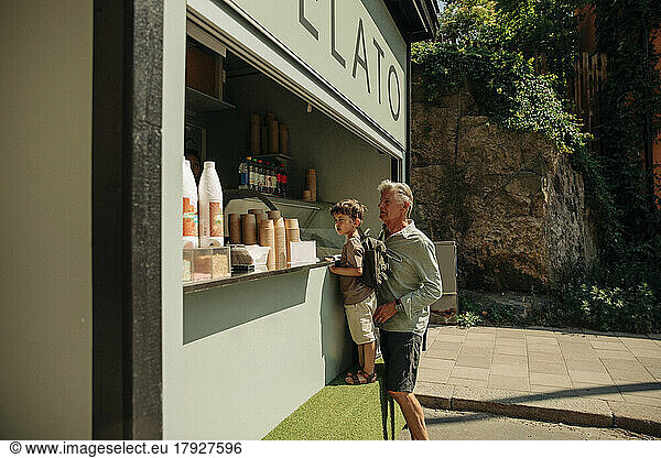 Grandfather and grandson buying ice cream from concession stand