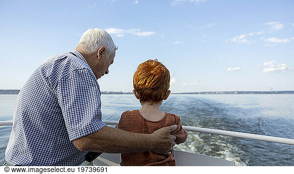 Grandfather and grandson looking at sea from ship