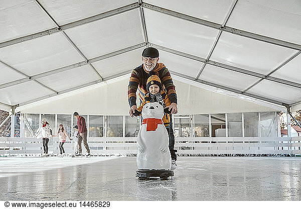 Grandfather and grandson on the ice rink  ice skating  using ice bear figure as prop