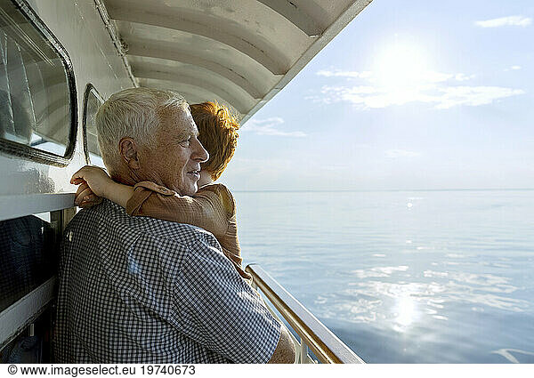 Grandfather carrying grandson and looking at sea from ship