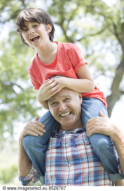 Grandfather carrying grandson on shoulders outdoors