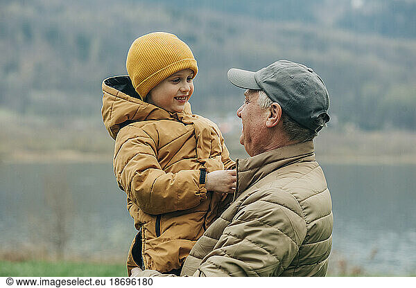Grandfather carrying grandson wearing warm clothing
