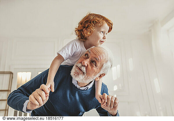 Grandfather giving piggyback ride to grandson at home