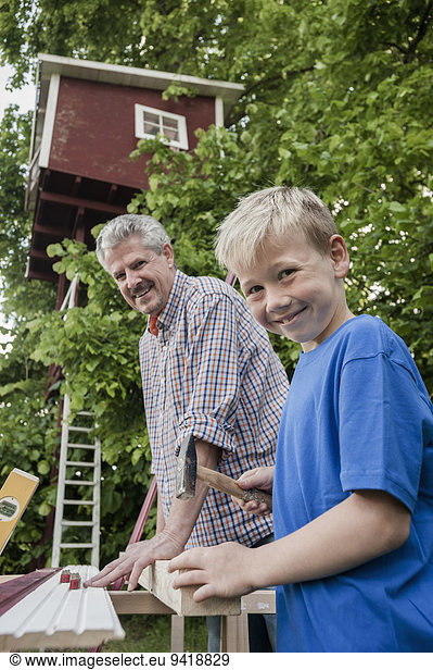 Grandfather grandson working together tree-house