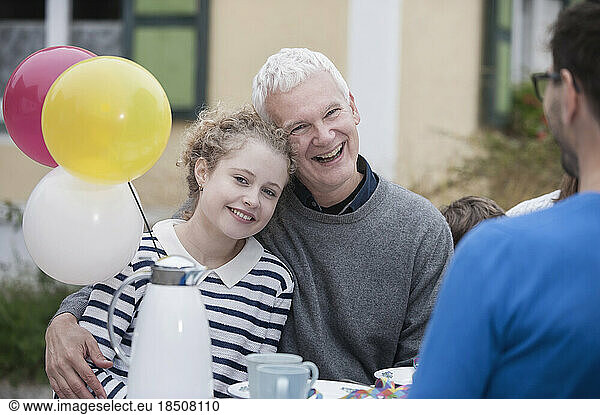 Grandfather hugging his granddaughter on her birthday party and smiling  Bavaria  Germany