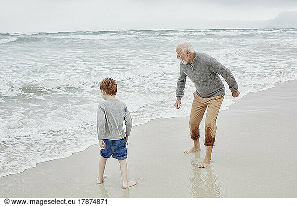 Grandfather playing with grandson at the sea