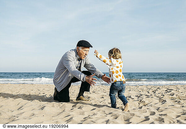 Grandfather playing with his granddaughter on the beach