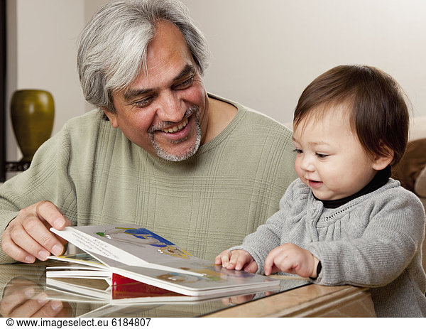 Grandfather reading book to granddaughter